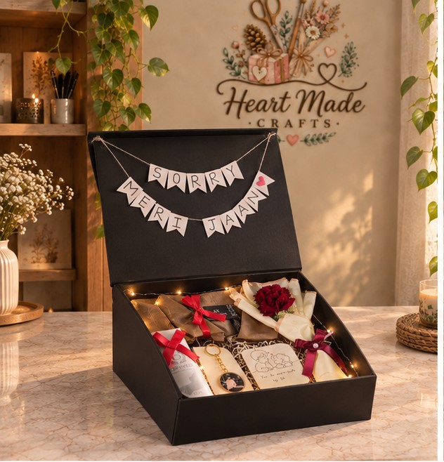 Premium open black romantic apology gift box featuring a handmade 'SORRY MERI JAAN' banner, red roses, wrapped gifts, personalized photo keychain, heartfelt message card and warm fairy lights, photographed from a front three-quarter angle.
